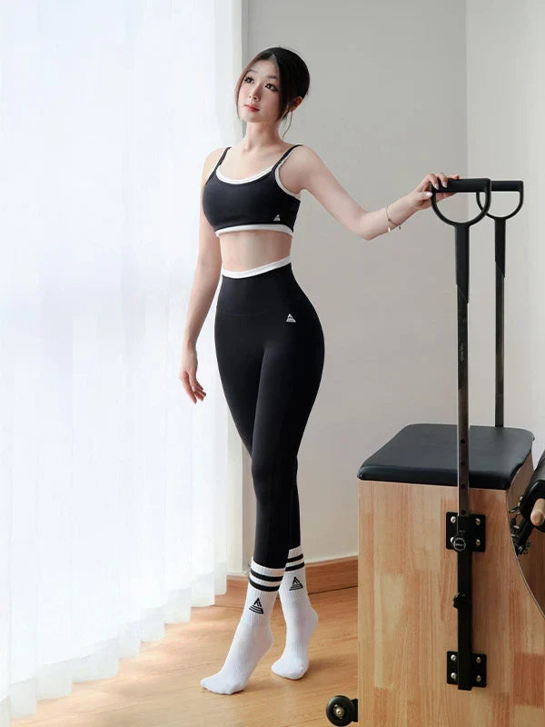 Cô gái nằm ngửa ôm hai gối vào ngực trên thảm, mặc legging và bra Fitme